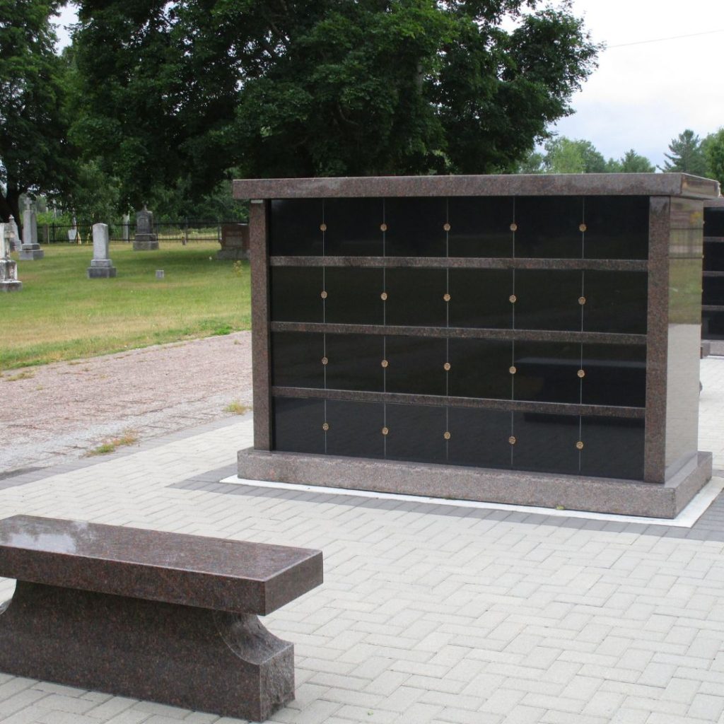 Granite parish columbarium with memorial niches and seating area.