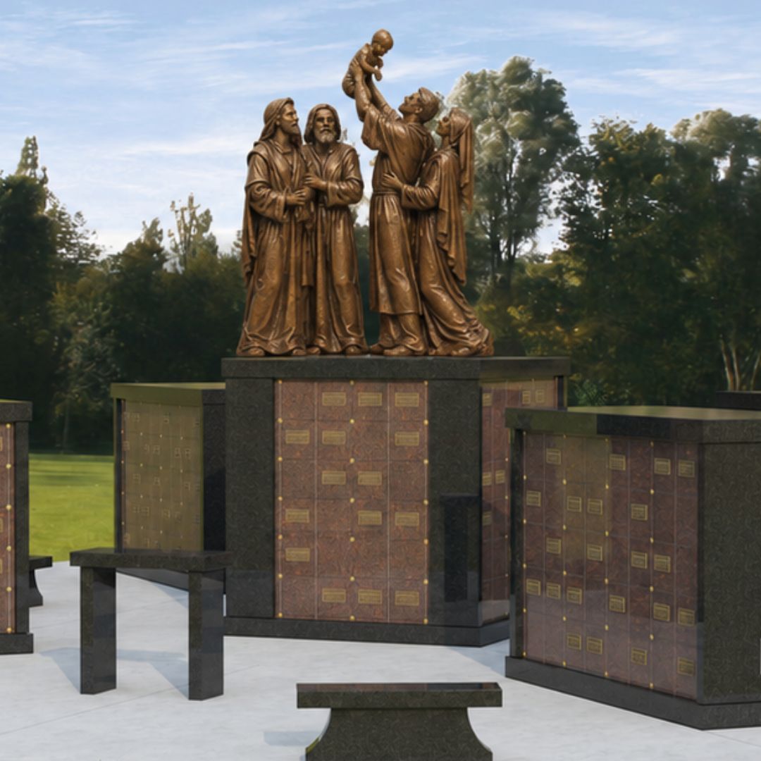 Bronze Holy Family sculpture integrated into a Catholic columbarium memorial garden.